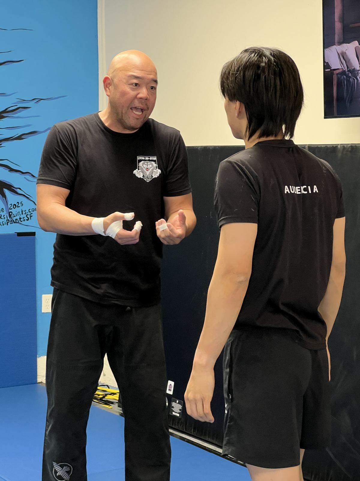 A coach in a black T-shirt explains a technique face to face with a newcomer.